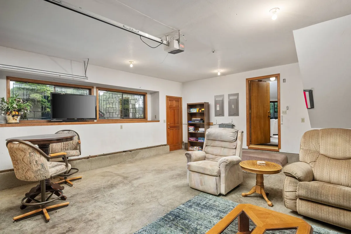 A tranquil reading and relaxation nook with a plush recliner chair, small round table, bookshelf, and large window letting in natural light. The space is ideal for quiet moments away from the excitement of local events.