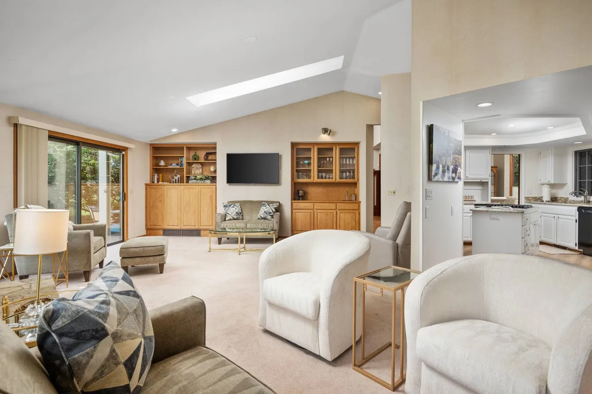 A cozy family room with large windows, comfortable seating with decorative pillows, wooden cabinetry, and an inviting atmosphere ideal for relaxation, movie nights, or casual conversations.