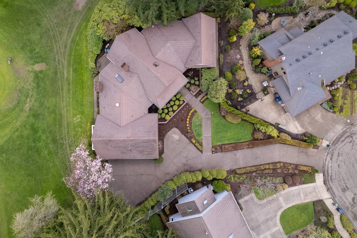 A broader exterior view of the main house surrounded by an impeccably landscaped garden. Curved driveways and glimpses of the neighboring houses enhance the peaceful, secluded feel. Spring blossoms and sunset lighting further underscore the sanctuary atmosphere.