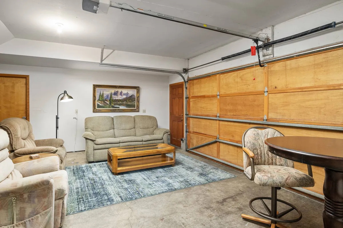 A comfortable living room with a cozy sofa set, a central coffee table, stylish bar stool seating, and artwork adorning the walls. The room is arranged to encourage relaxed conversations, board games, or unwinding after a busy day exploring Eugene.
